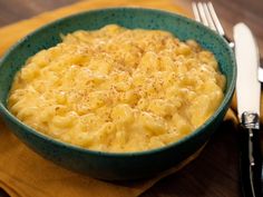 a green bowl filled with macaroni and cheese on top of a wooden table