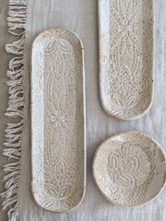 three white plates sitting on top of a table next to each other with tassels