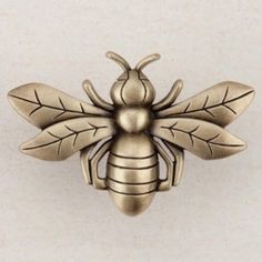 a brass bee brooch sitting on top of a white surface