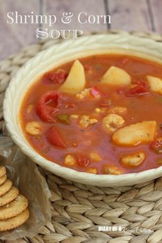 a bowl of shrimp and corn soup next to crackers on a wicker table