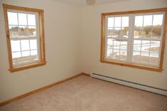 an empty room with two windows and no carpeting on the floor in front of them