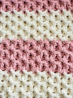 the crocheted blanket is pink, white and beige with two stripes on it