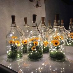 there are many glass bottles with flowers in them and some lights on the top one