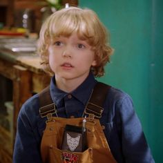 a young boy with blonde hair wearing an apron