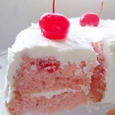 a piece of cake with white frosting and cherries on top is being held up