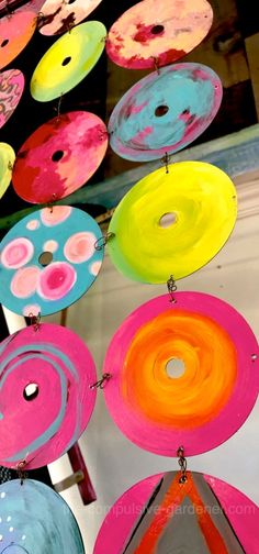 colorful paper plates are hanging from strings in the air, with circles painted on them