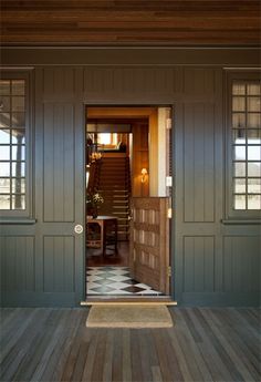 an open door leading into a room with wooden floors and walls, along with a checkered rug on the floor