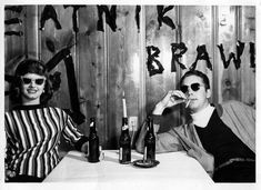 two women are sitting at a table with wine bottles and glasses on their heads, posing for the camera