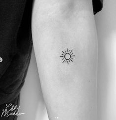 a black and white photo of a sun tattoo on the arm