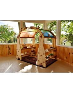 a child's play area in the corner of a room with wood paneling and windows