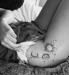 a woman is laying on her stomach with tattoos on her legs and the sun and moon