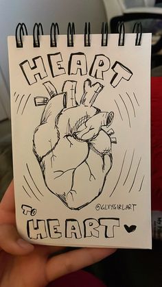 a hand holding up a drawing of a heart