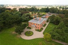 an aerial view of a large brick house surrounded by trees