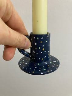 a person holding a candle in a blue cup with white and yellow dots on it