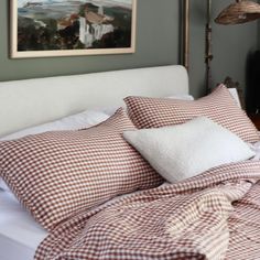 a bed with red and white gingham comforter on top of it next to a lamp