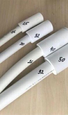 four white plastic tubes sitting on top of a wooden table with numbers printed on them