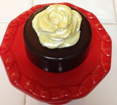 a red plate topped with a chocolate cake covered in white frosting on top of a tile floor