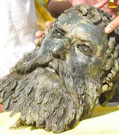 a close up of a statue of a man's face with his hands on it