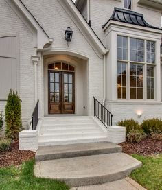 a white house with steps leading up to the front door and entry way that leads into the yard