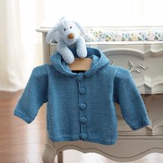 a blue knitted sweater with a white teddy bear on it and the words neat as a button