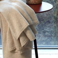 a towel draped over a table next to a vase with flowers on it and a window in the background