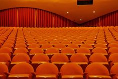 an empty auditorium with rows of orange chairs