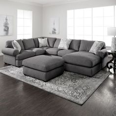 a large sectional couch in a living room with hardwood floors and white walls, along with an area rug on the floor