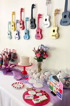 a table topped with lots of different types of cakes and guitars on the wall behind it