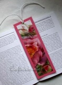 an open book with pink flowers on the pages and a string hanging from it's cover