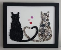 a framed picture with buttons in the shape of two cats and a cat's tail