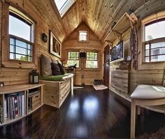 the interior of a tiny cabin with wood flooring and windows on each side of the room