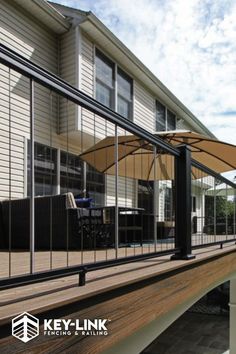 an outdoor deck with umbrellas and chairs on the side of it in front of a house