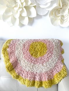 a white couch sitting next to a wall with paper flowers on it and a rug in the shape of a flower