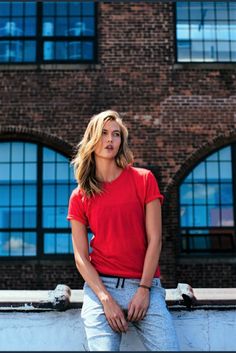 a woman leaning against a wall with her hands on her hips and looking off to the side