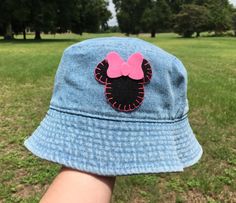 a child's hat with a pink minnie mouse patch on it in the grass