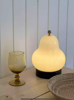 a table topped with a lamp next to a bowl and glass vase on top of it