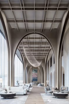 the interior of a large building with high ceilings and arched arches, white couches and chairs