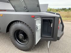 the back end of a vehicle with its door open and wheels down, parked in a parking lot