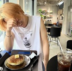 a woman sitting at a table with a plate of food in front of her face