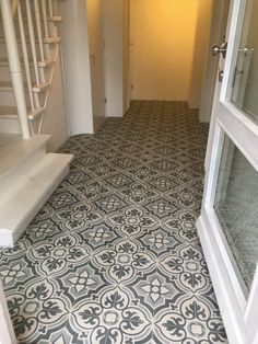 an empty hallway with stairs and tiled flooring