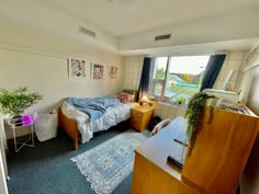 a bedroom with a bed, desk and window in it's corner area next to a rug