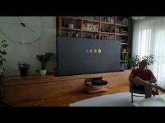 a man sitting on a chair in front of a flat screen tv with google logo