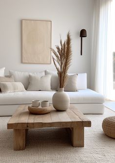 a living room with white couches, pillows and a coffee table in front of a large window