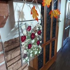 an autumn scene with flowers and leaves hanging from a window frame in front of a brick fireplace