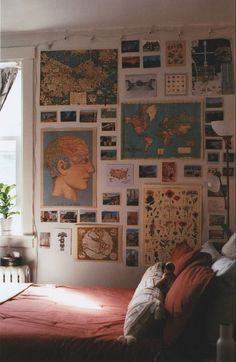 a bed sitting under a window next to a wall covered in pictures