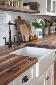 a kitchen with white cabinets and wooden counter tops, along with a black faucet