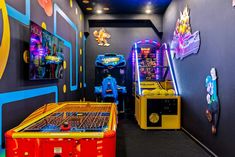 several arcade machines lined up against a wall in a playroom with video games on the walls