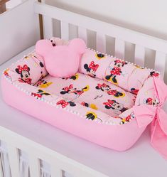 a baby crib with minnie mouse bedding on it