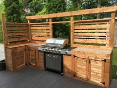 an outdoor kitchen made out of wood with grill and cabinets on the outside deck area