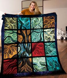 a woman is holding up a colorful quilt